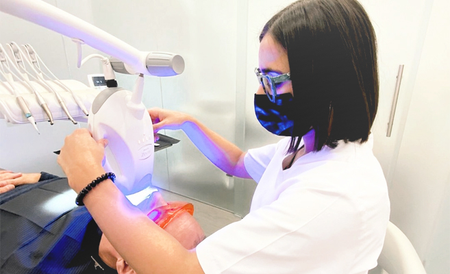 Odontóloga realizando tratamiento dental con lámpara de luz en la Clínica Alberto García Valladolid